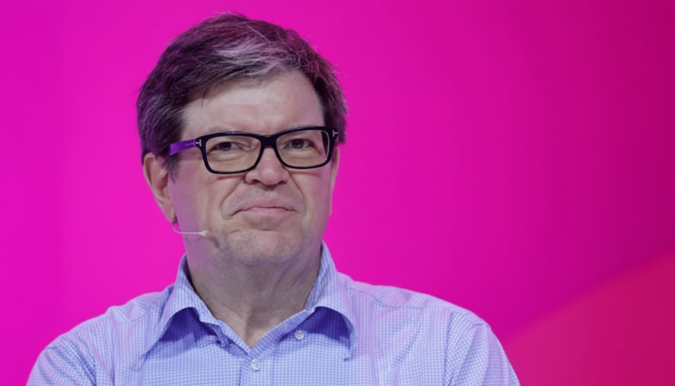 A man with glasses and a light blue shirt against a bright pink background, resized to a 16:9 aspect ratio.