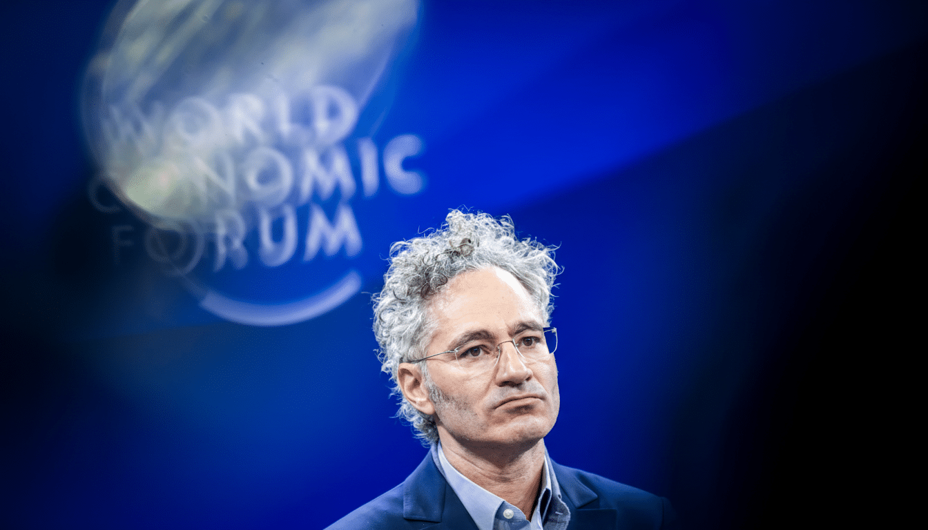 A man with curly grey hair and glasses, wearing a suit jacket and collared shirt, looks thoughtfully to the side against a blue background with the World Economic Forum logo blurred in the background.