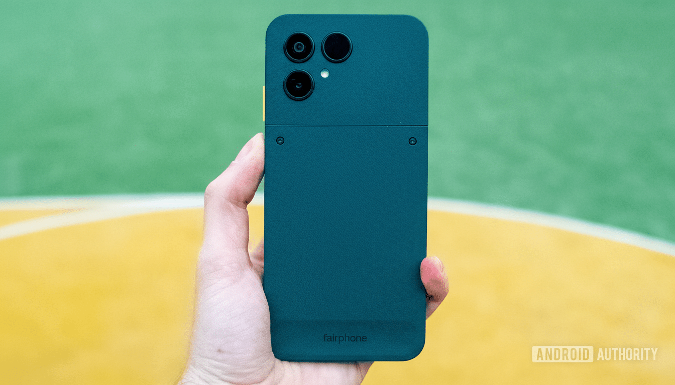 A hand holding a Fairphone in a 16:9 aspect ratio, with the original green and yellow background.