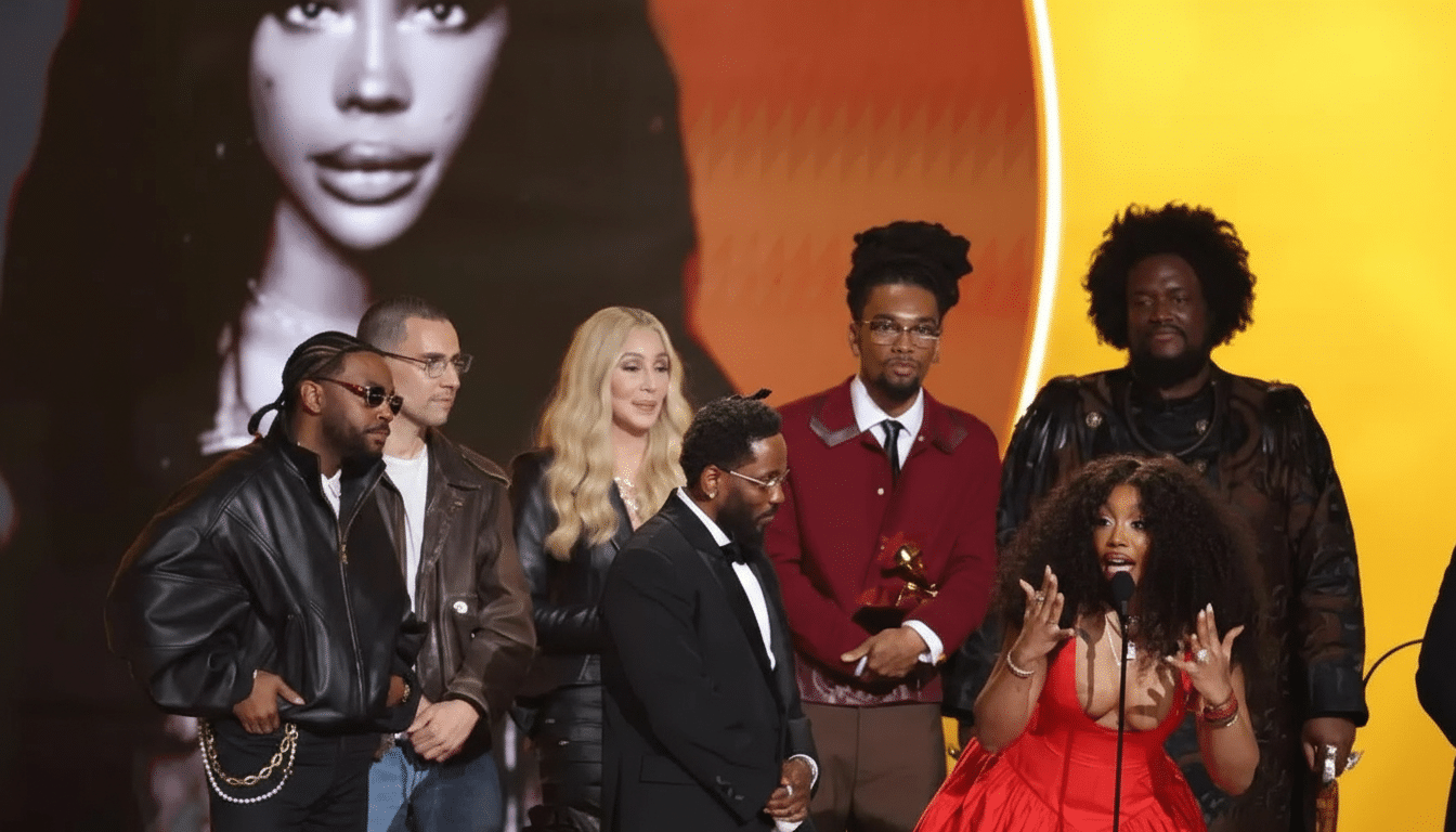 A group of people on stage at an awards ceremony, with a large screen behind them displaying a womans face.
