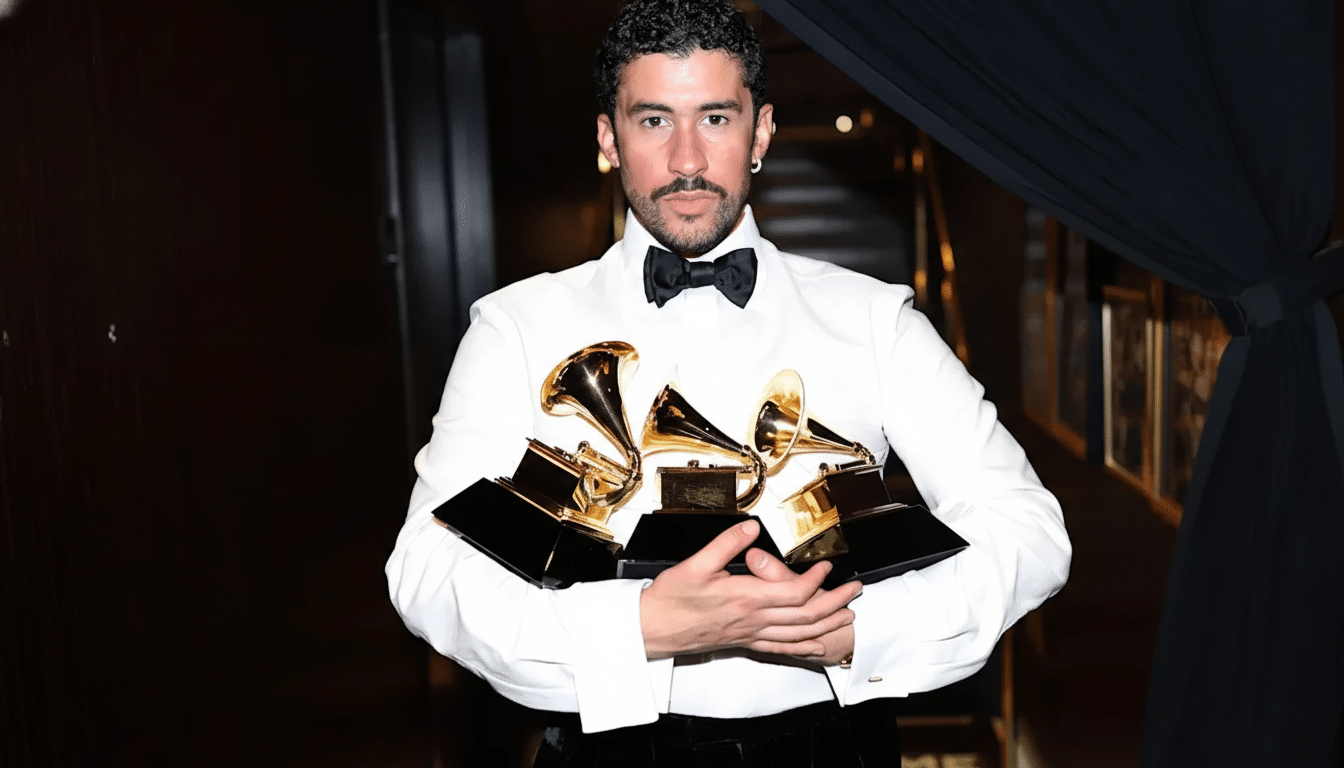 A man in a white shirt and black bow tie holding three Grammy awards.