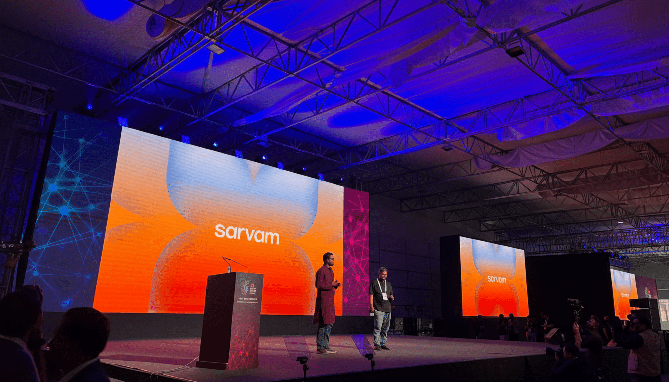 Two men standing on a stage in front of large screens displaying the sarvam logo, with an audience visible in the foreground.