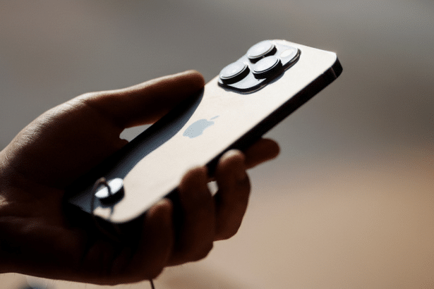 A hand holding an iPhone in a 16:9 aspect ratio, with the original background maintained.