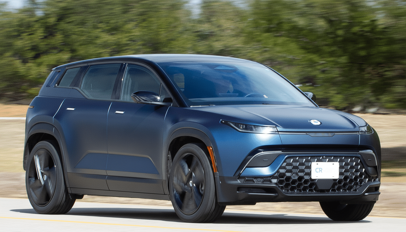 A dark blue Fisker Ocean electric SUV driving on a road with a blurred green background.