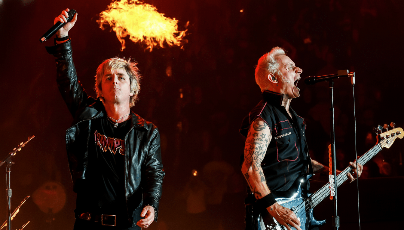 Two male musicians performing on stage with flames in the background.