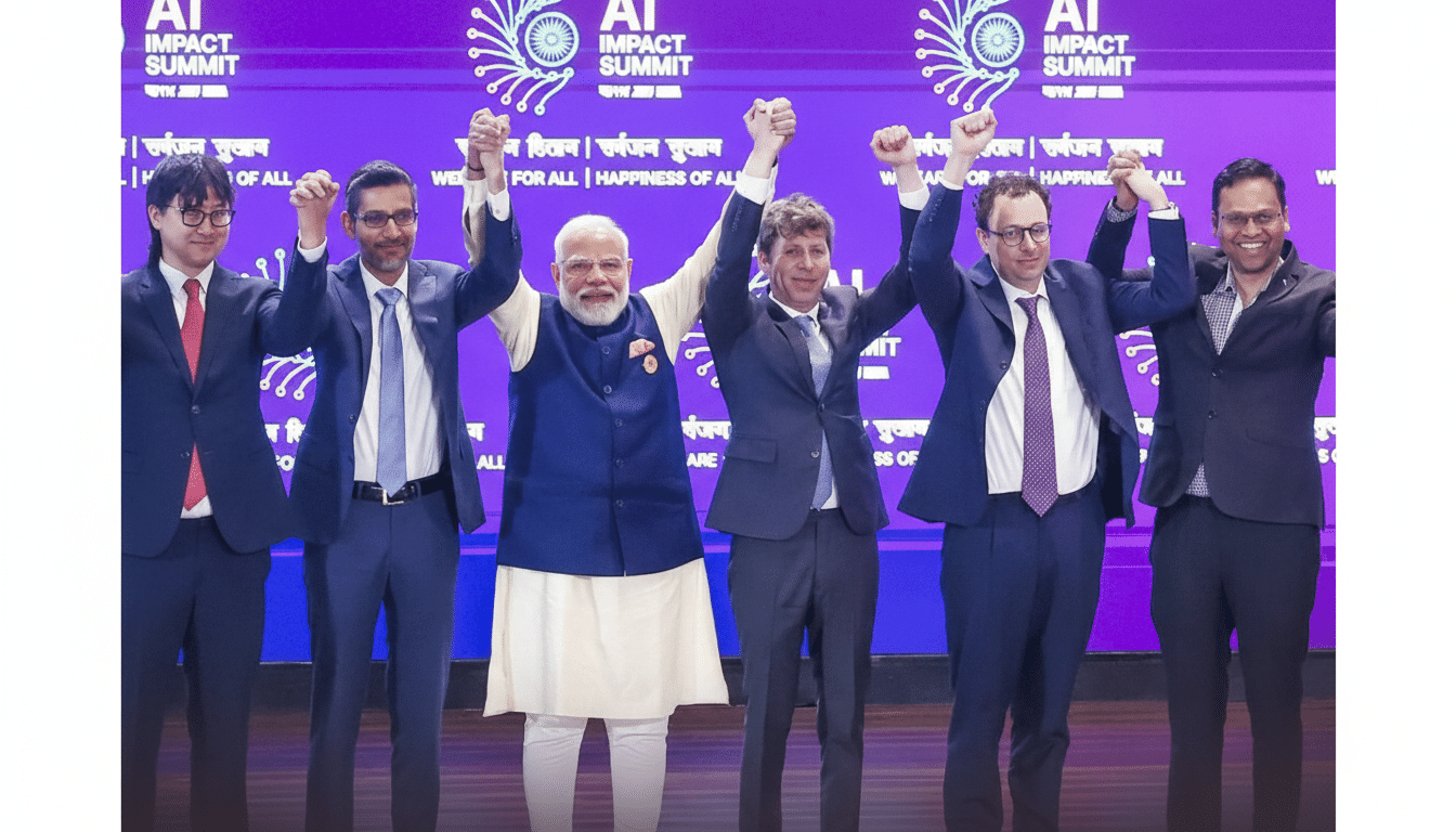 A group of six men, including Prime Minister Narendra Modi, stand on a stage with their hands raised and joined, celebrating at the AI Impact Summit.