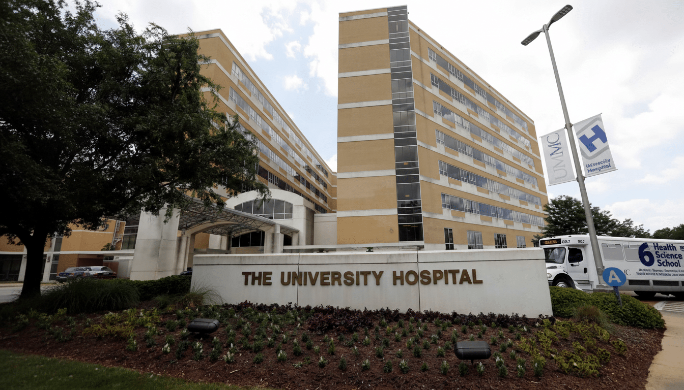 The University Hospital building with a sign in front and a bus parked nearby.