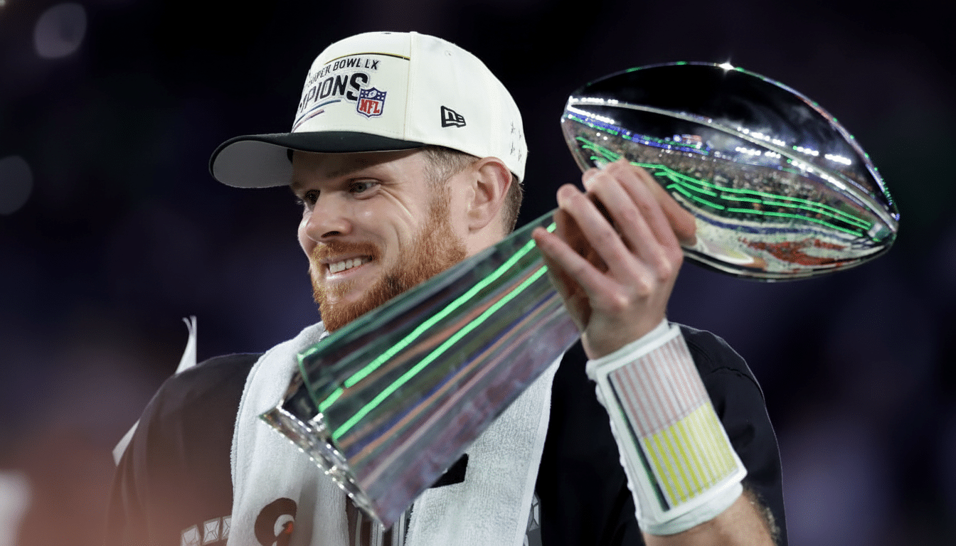 A man with a beard and a white Super Bowl LIX Champions hat smiles while holding a silver trophy.