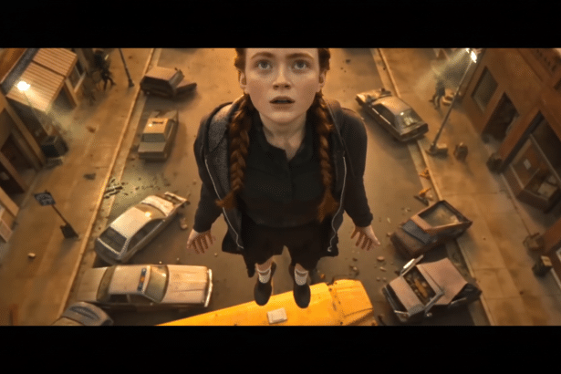A young woman with braided hair floats above a street filled with overturned cars and debris, looking up with a surprised expression.
