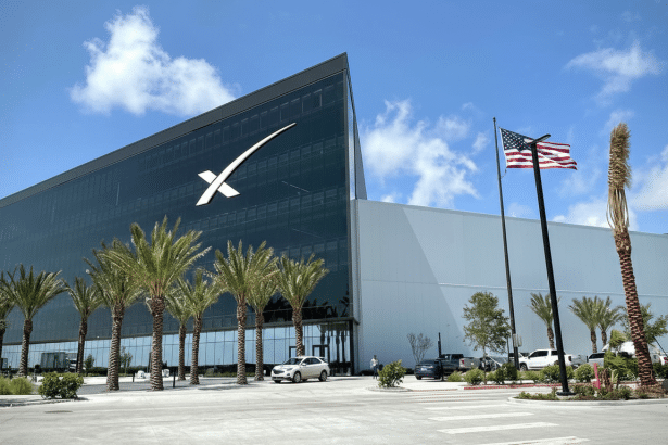 A 16:9 aspect ratio image of the SpaceX headquarters building with palm trees and an American flag.