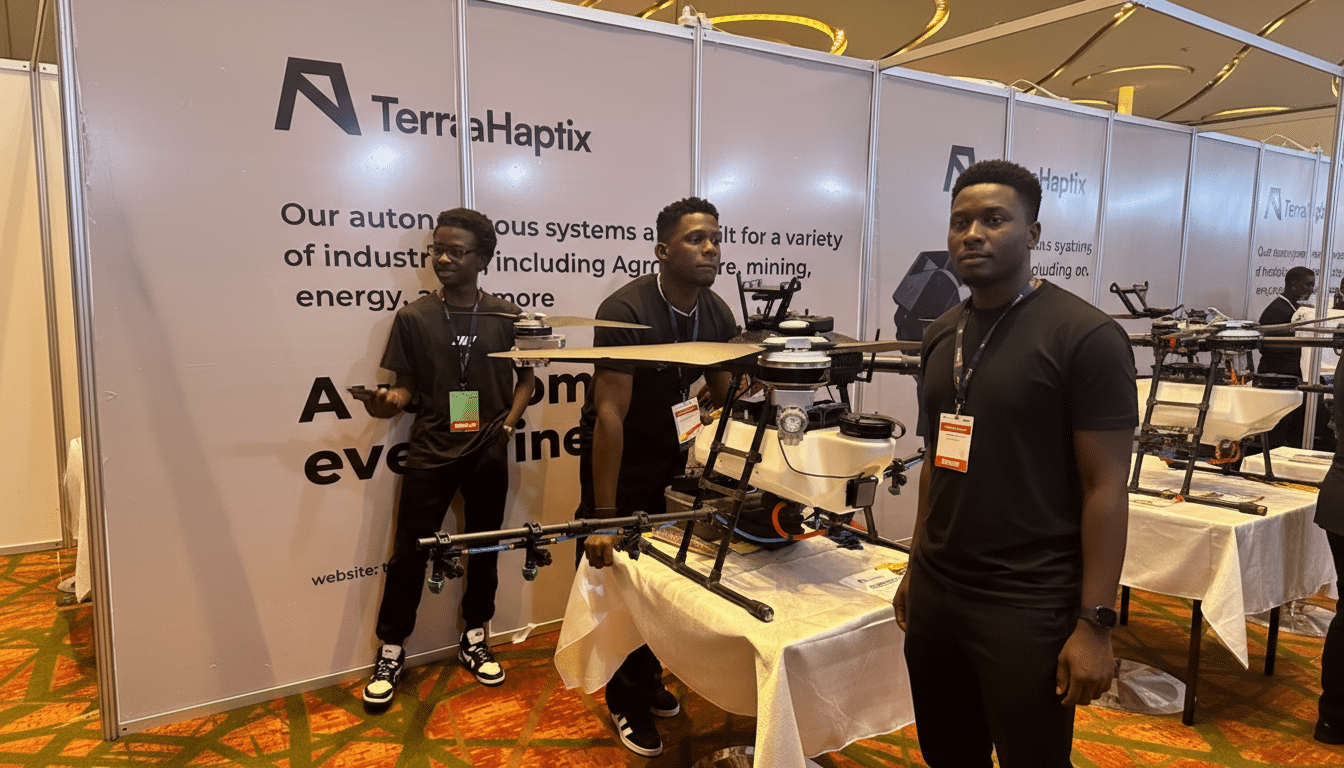 Three men standing in front of a TerraHaptix booth with a large drone on display.