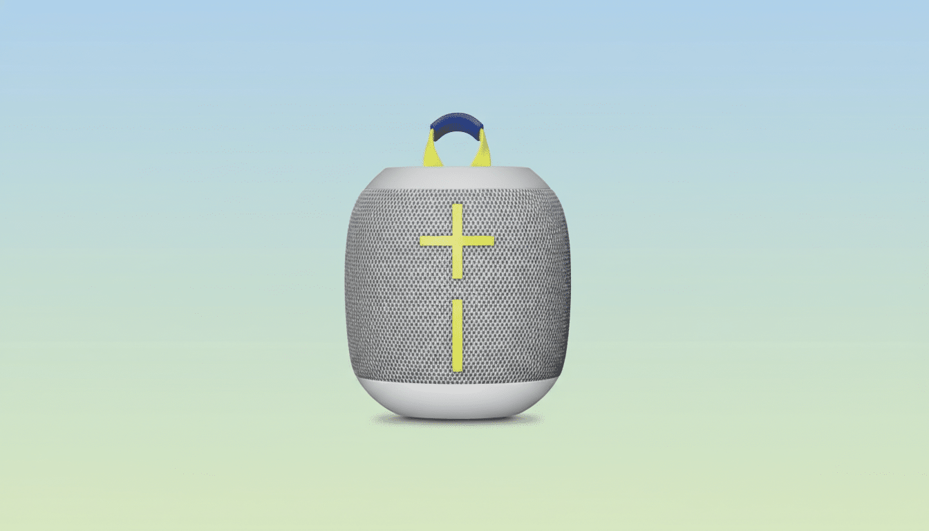 A gray portable speaker with a yellow plus and minus sign on the front, a yellow strap, and a blue handle, set against a soft gradient background of light blue and green.