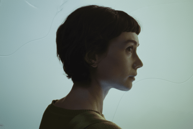 A woman with short dark hair in profile, looking to the right, against a light blue background with subtle wavy patterns.