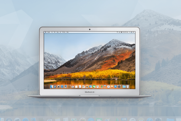 A silver MacBook Air laptop is centered on a light blue background with a subtle geometric pattern. The laptops screen displays a scenic mountain landscape with autumn foliage.