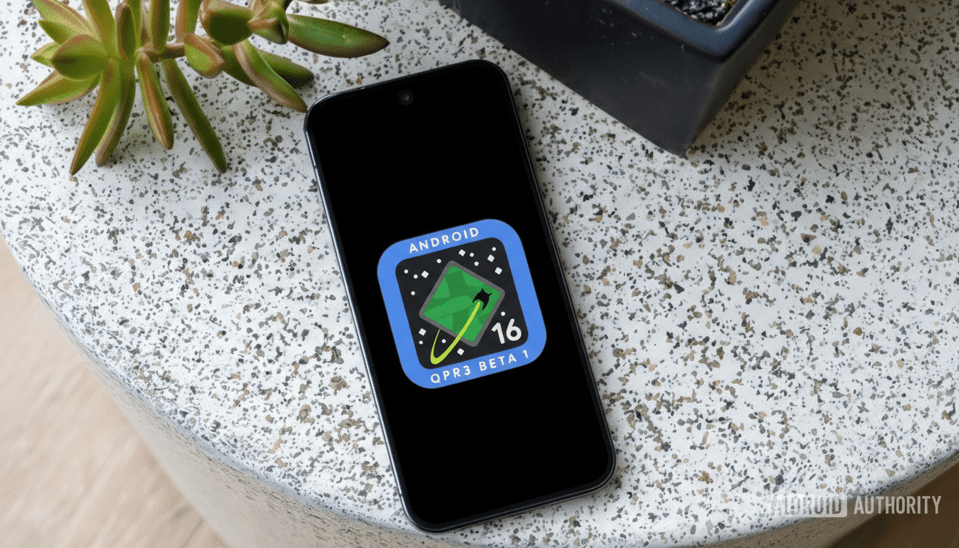 A smartphone displaying the Android QPR3 Beta 1 logo on its screen, set against a speckled white surface with a green plant and a dark pot in the background.