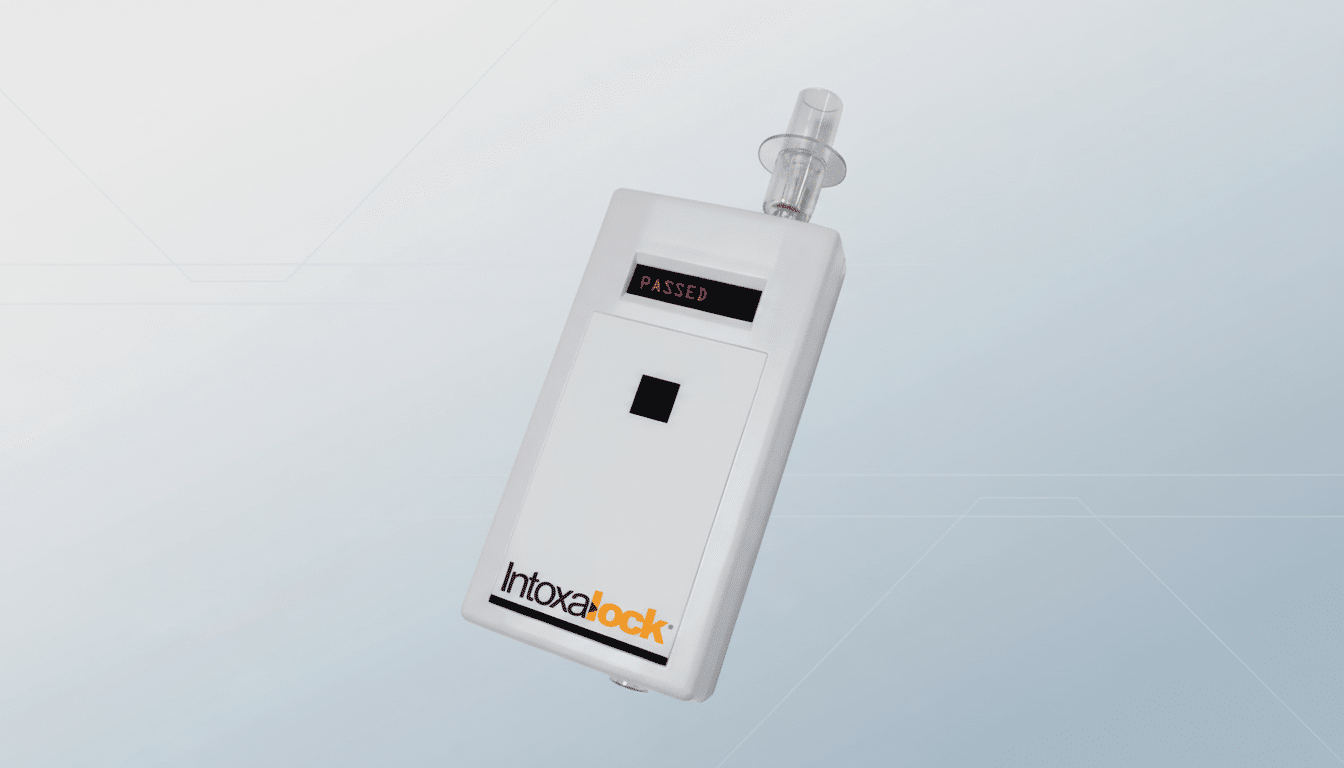 A white Intoxalock breathalyzer device displaying PASSED on its screen, set against a professional light gray background with subtle geometric patterns.