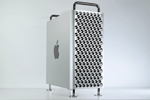 A silver Apple Mac Pro desktop computer with a perforated front panel and handles, set against a professional light gray background with subtle geometric patterns.