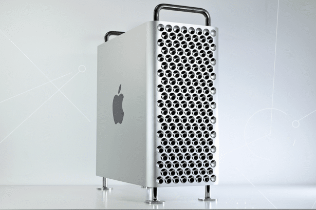 A silver Apple Mac Pro desktop computer with a perforated front panel and handles, set against a professional light gray background with subtle geometric patterns.