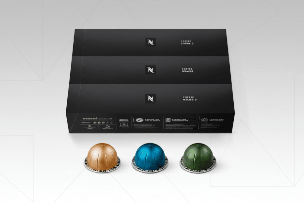 A 16:9 aspect ratio image of three black Nespresso coffee boxes stacked, with three colorful coffee capsules (gold, blue, and green) in front, set against a professional flat design background with soft patterns.