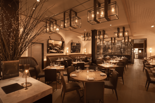 A professionally enhanced image of a restaurant interior, resized to a 16:9 aspect ratio, featuring warm lighting, set tables, and a stylish, modern design.