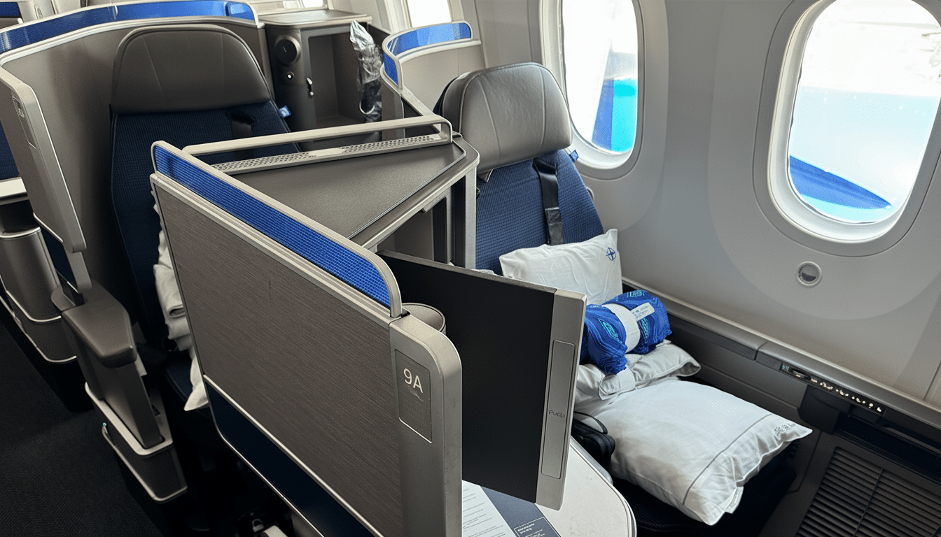 A professional photograph of an airplanes business class cabin, featuring spacious seats, a tray table, and a window view.