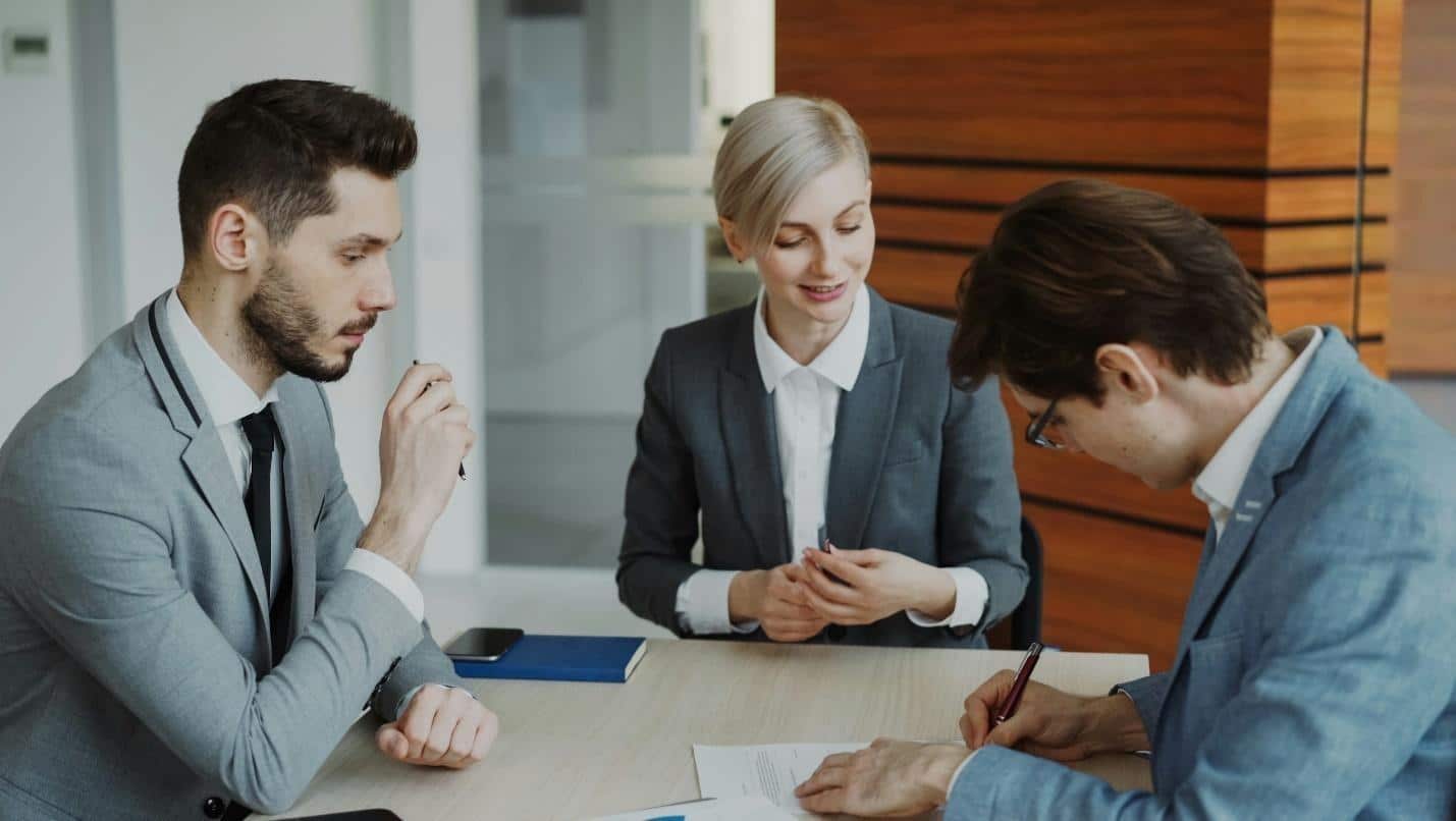 Business people signing a contract at a table. Business people signing a contract at a table.